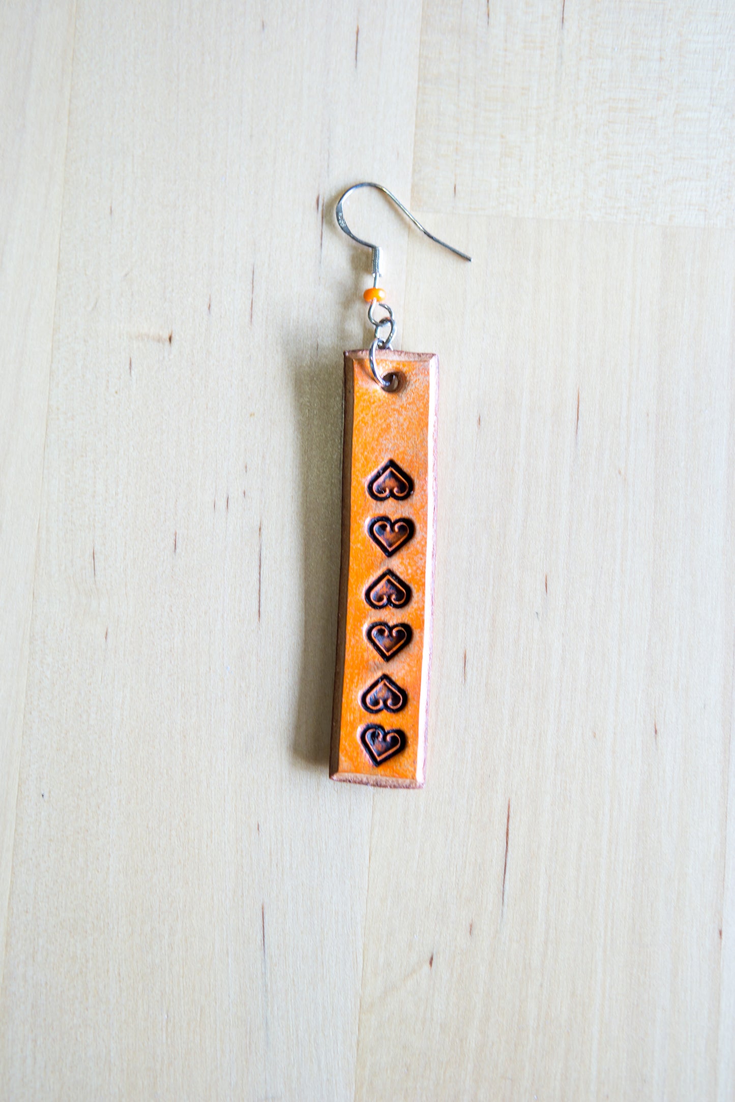 Brincos artesanais de couro formato barra – motivos abstratos laranja