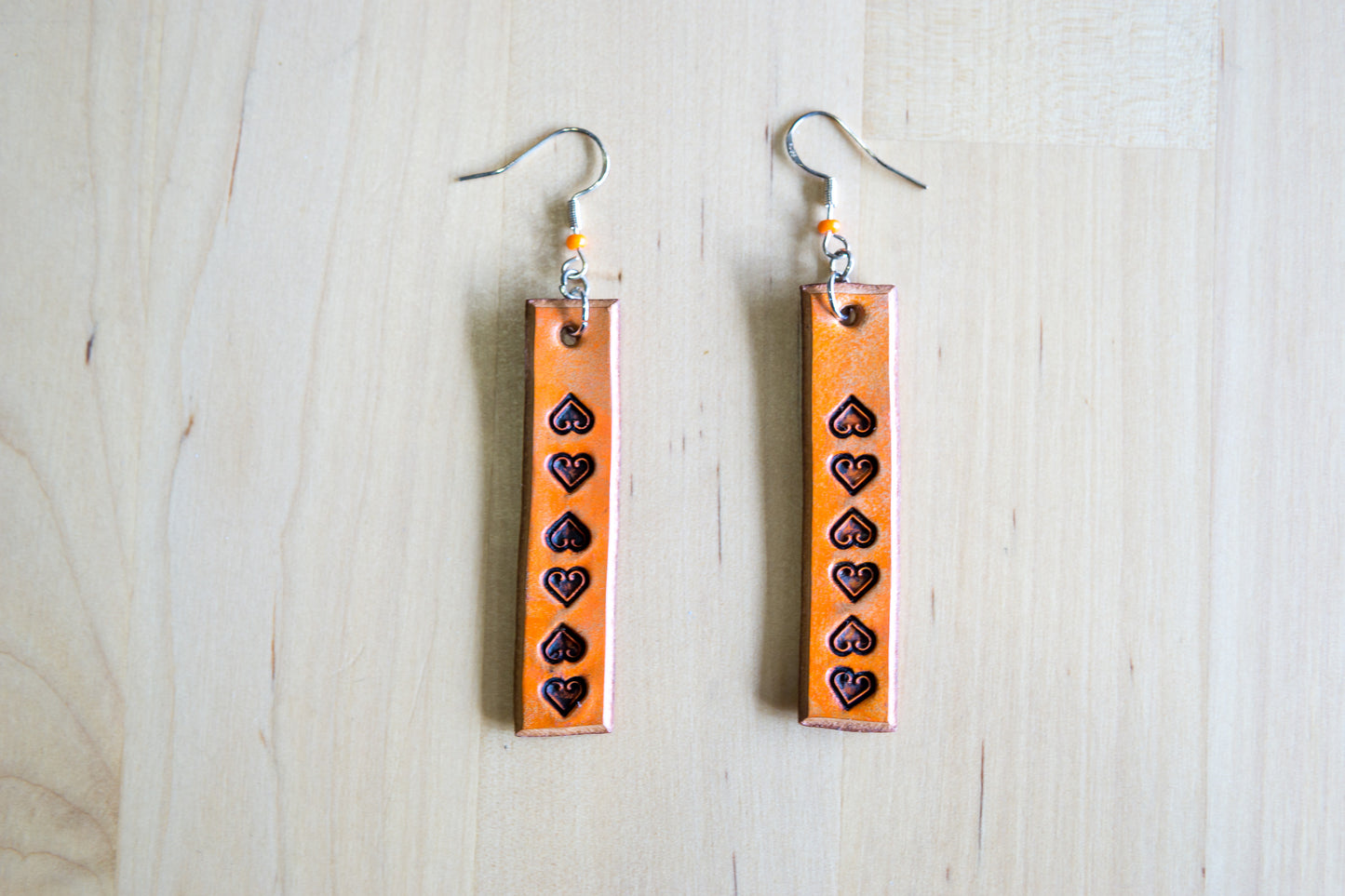 Brincos artesanais de couro formato barra – motivos abstratos laranja